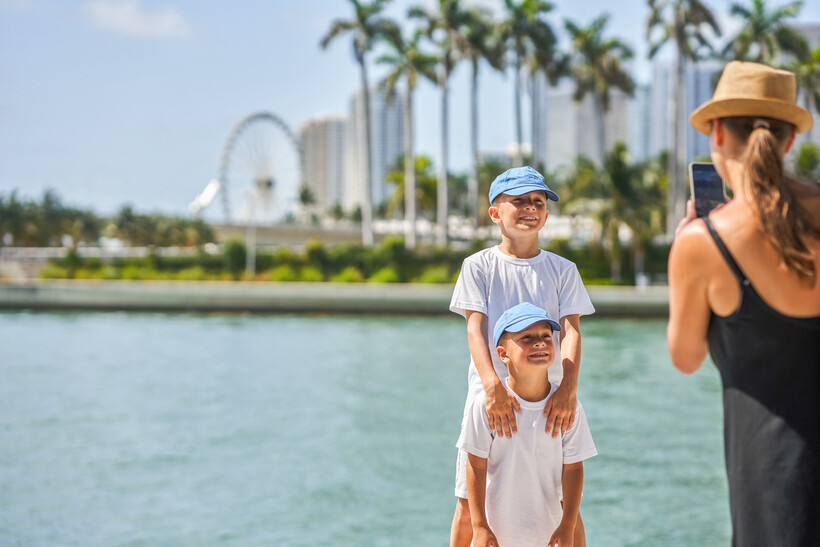 A mother using her smartphone to take a photo of her sons in Miami. - moving to Miami