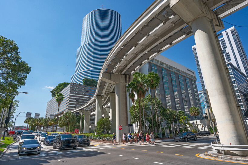 The elevated Metrorail train moving through the modern glass buildings of downtown Miami. - moving to Miami