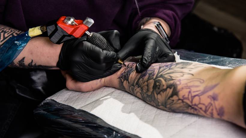 Close-up of a tattooist working on an intricate arm piece, demonstrating the precision required for those learning how to make money as a tattoo artist.
