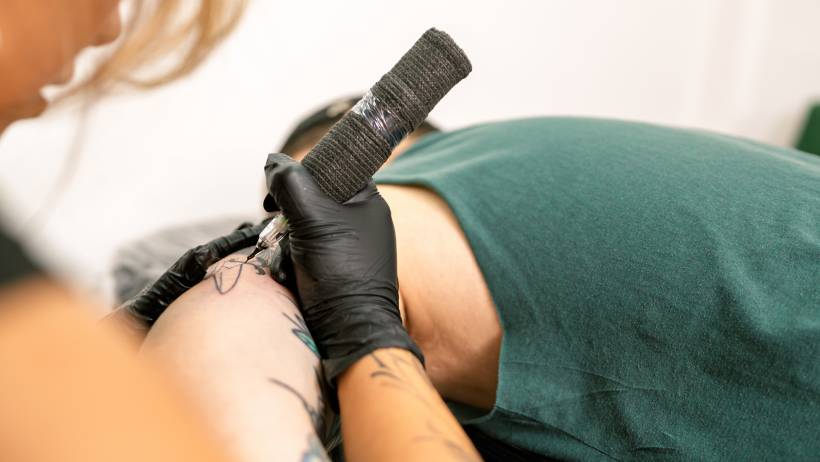 Professional at work on a shoulder piece, highlighting the technical equipment and skill used to make money as a tattoo artist.