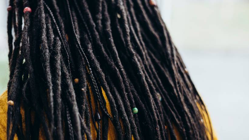 Back view of long, dark brown and black hair in a woman hairstyle dreadlocks decorated with small colorful wooden beads. - dreadlocks cost