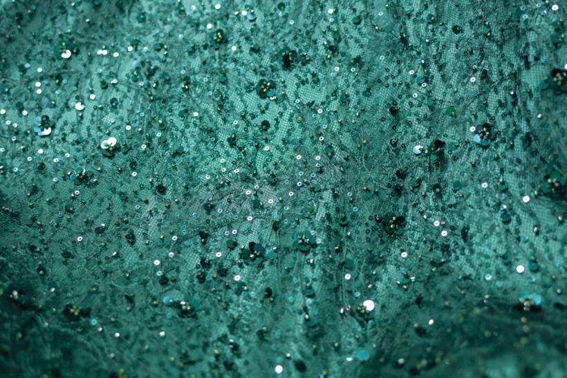 dress alterations cost - Detailed texture of green lace fabric with sequins for evening wear