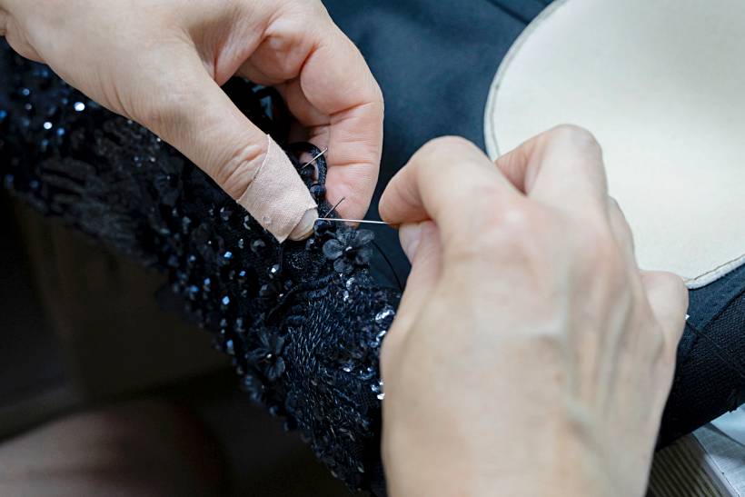 dress alterations cost - Close-up of hands performing dress alterations on black sequin fabric