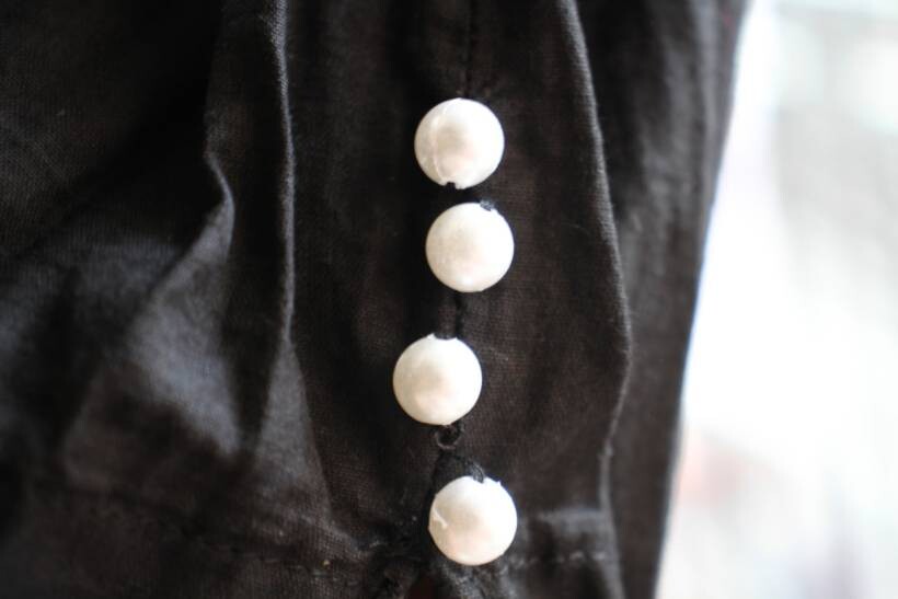 dress alterations cost - Black dress fabric with hand-stitched white buttons for closure