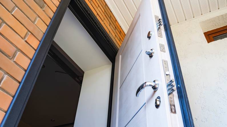 An open secure storm door showing a multi-point locking system with three steel deadbolts and a polished chrome handle. - storm door installation cost