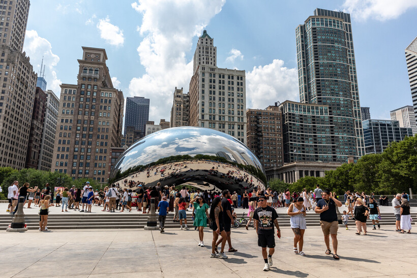 People walking around the silver Cloud Gate art installation in downtown Millennium Park. - moving to Chicago