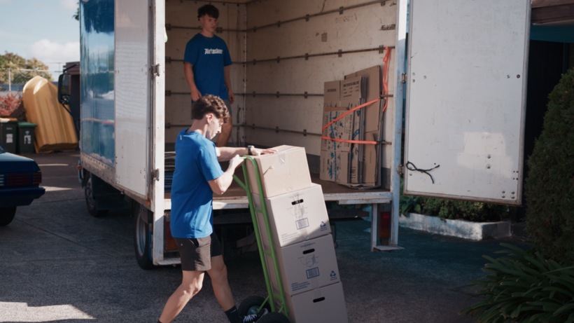 Two movers loading heavy cardboard boxes onto the back of a moving truck. - moving to Chicago