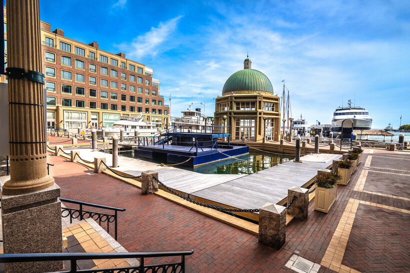 Waterfront view of downtown Boston with boats docked near a historic harbor pavilion. - moving to Boston