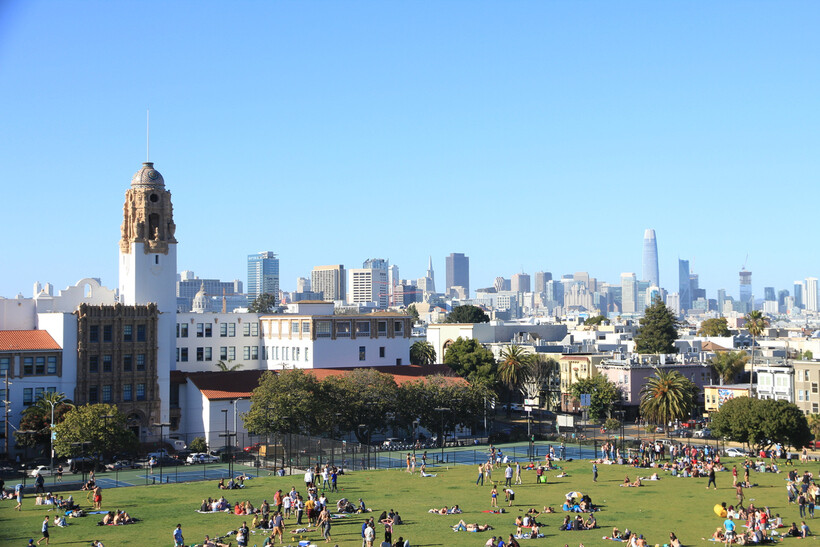 Groups of people relaxing on the grass at Mission Dolores Park with skyline views. - moving to San Francisco