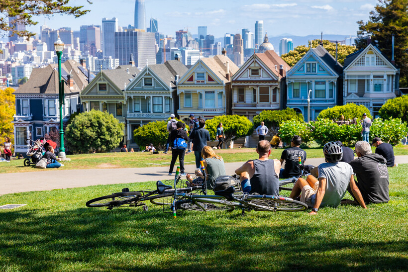 People sitting on the grass at Alamo Square Park facing the Painted Ladies houses. - moving to San Francisco