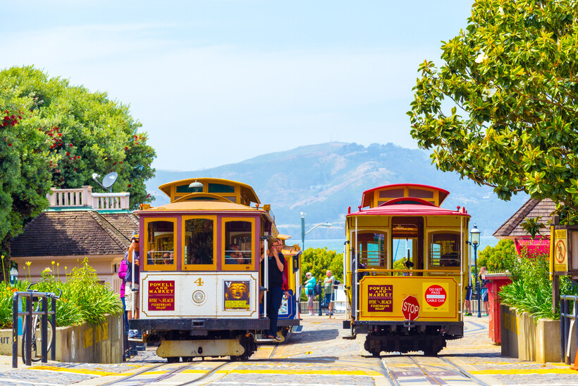 A historic cable car stopped at a turnaround station with passengers on board. - moving to San Francisco