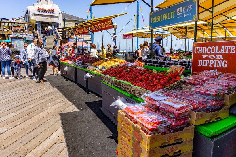 A vibrant display of oranges, apples, and berries at a Pier 39 fruit stand. - moving to San Francisco