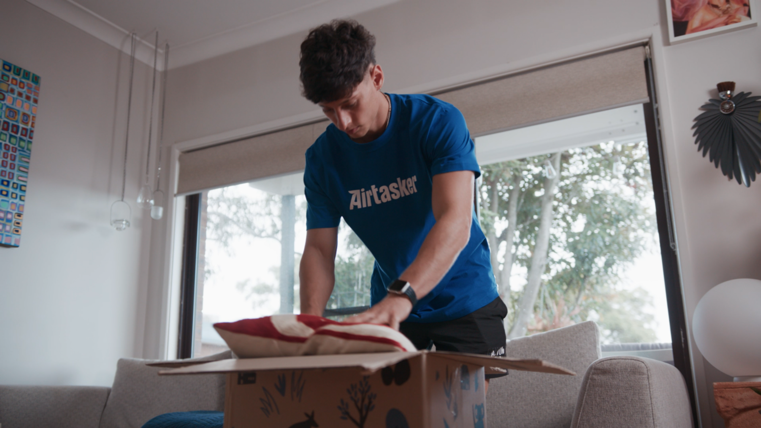 A pro mover packing a pillow inside a cardboard box.