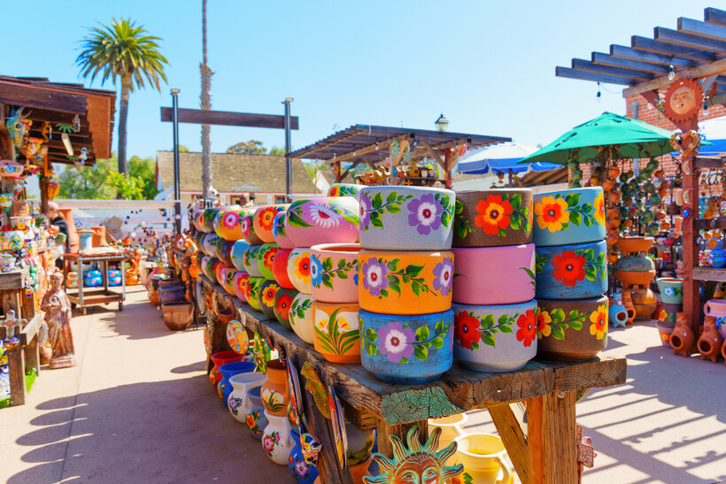 Colorful hand-painted floral ceramic bowls displayed for sale at an open market. - moving to San Diego