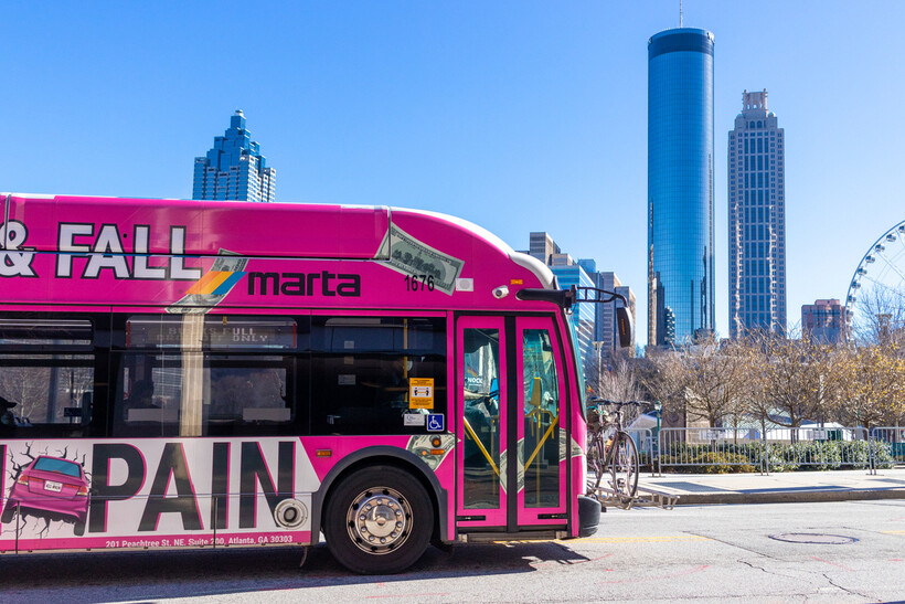Pink MARTA bus driving past Atlanta skyline on a clear day. - moving to Atlanta