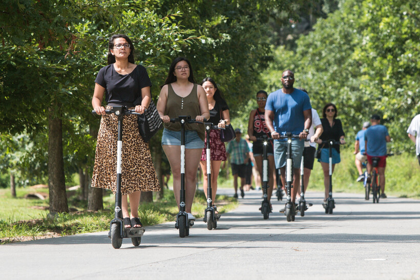 People riding motorized scooters along the paved Atlanta BeltLine multi-use trail. - moving to Atlanta