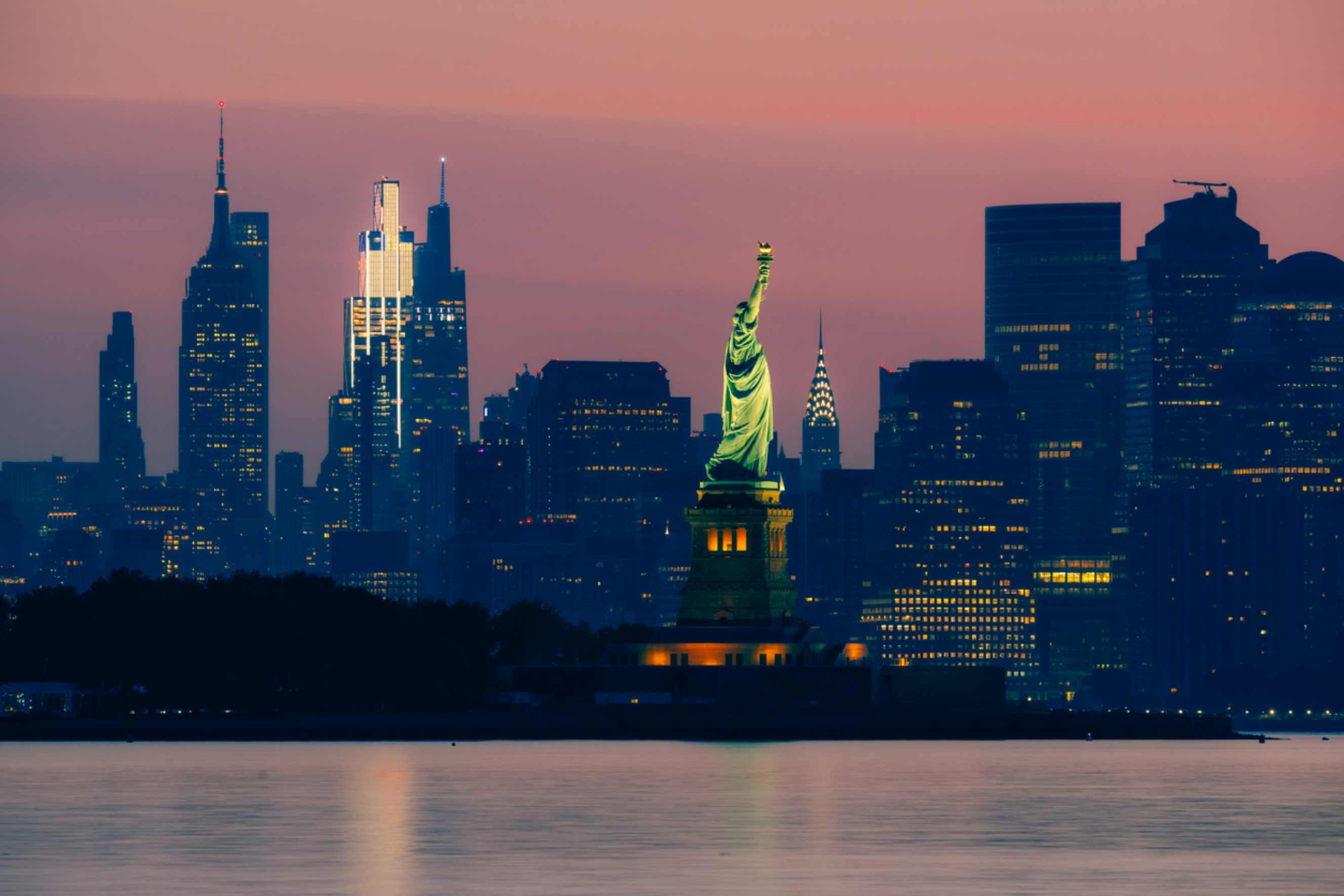 Statue of Liberty with the New York City skyline at dusk, a popular destination for people moving from Washington DC