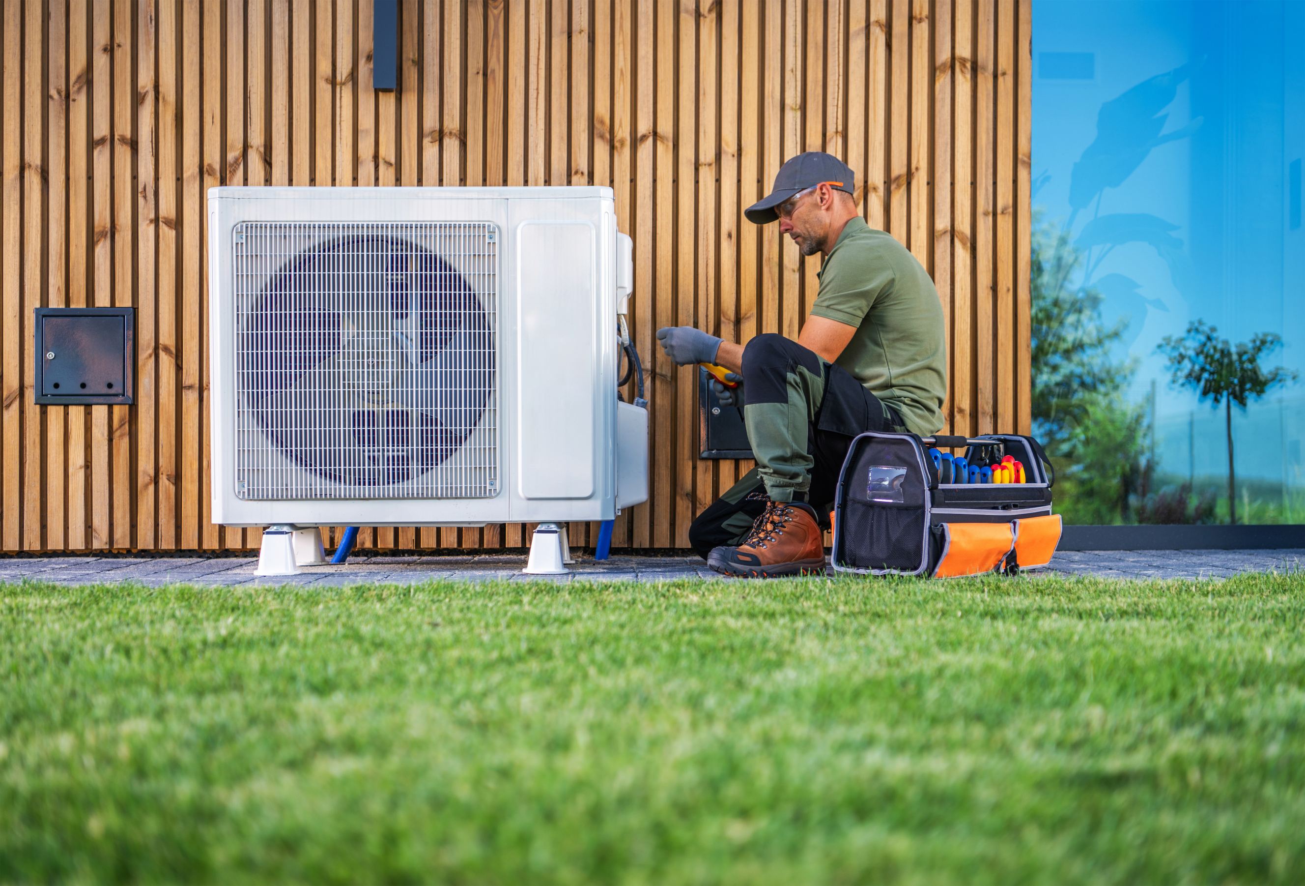 A technician is servicing an air HVAC unit located beside a modern home representing local HVAC repair near me.