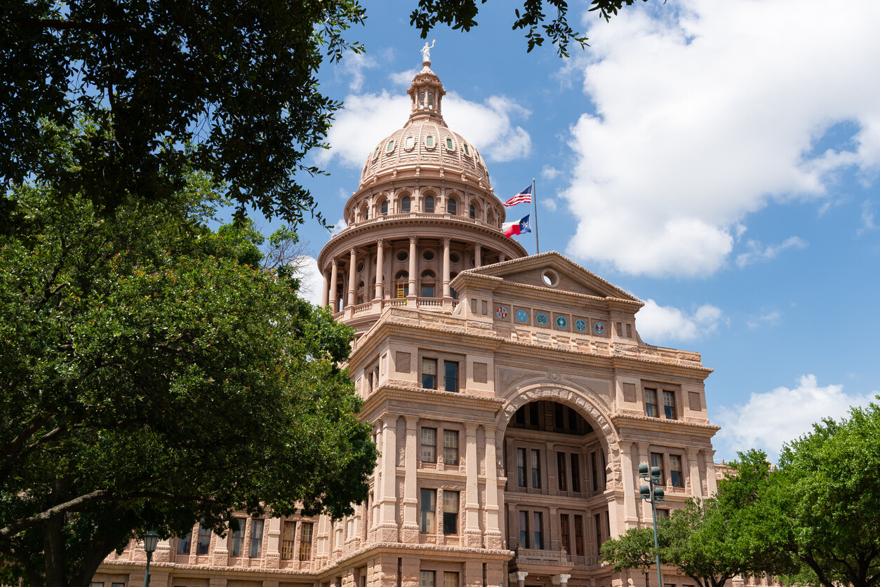 Texas State Capitol building in Austin framed by trees under a blue sky