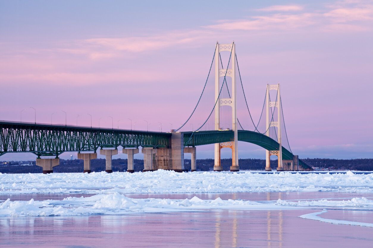 Mackinac Bridge in Michigan over icy water at sunset