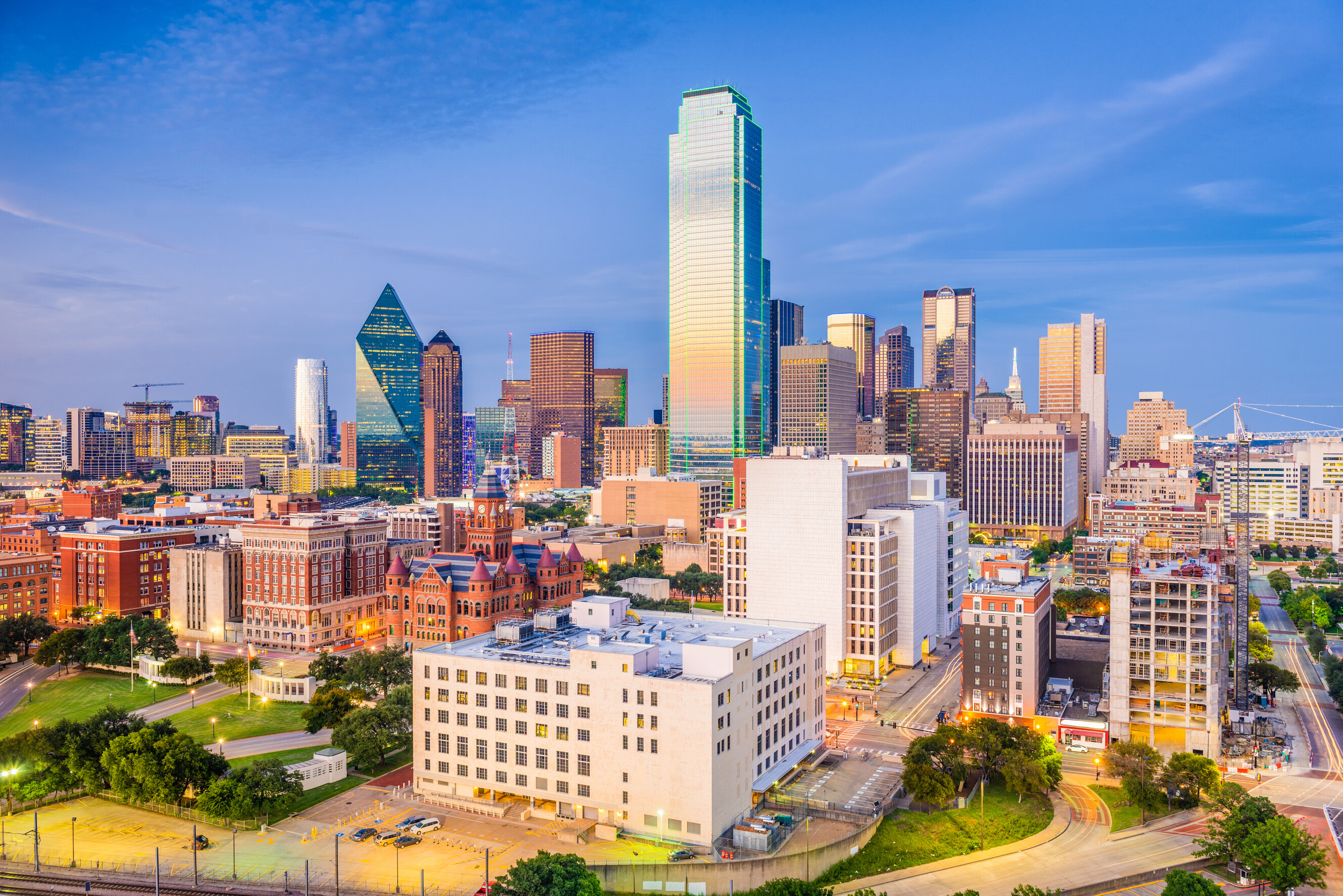 Wide view of Dealey Plaza featuring the historic Dallas skyline under a clear blue sky.