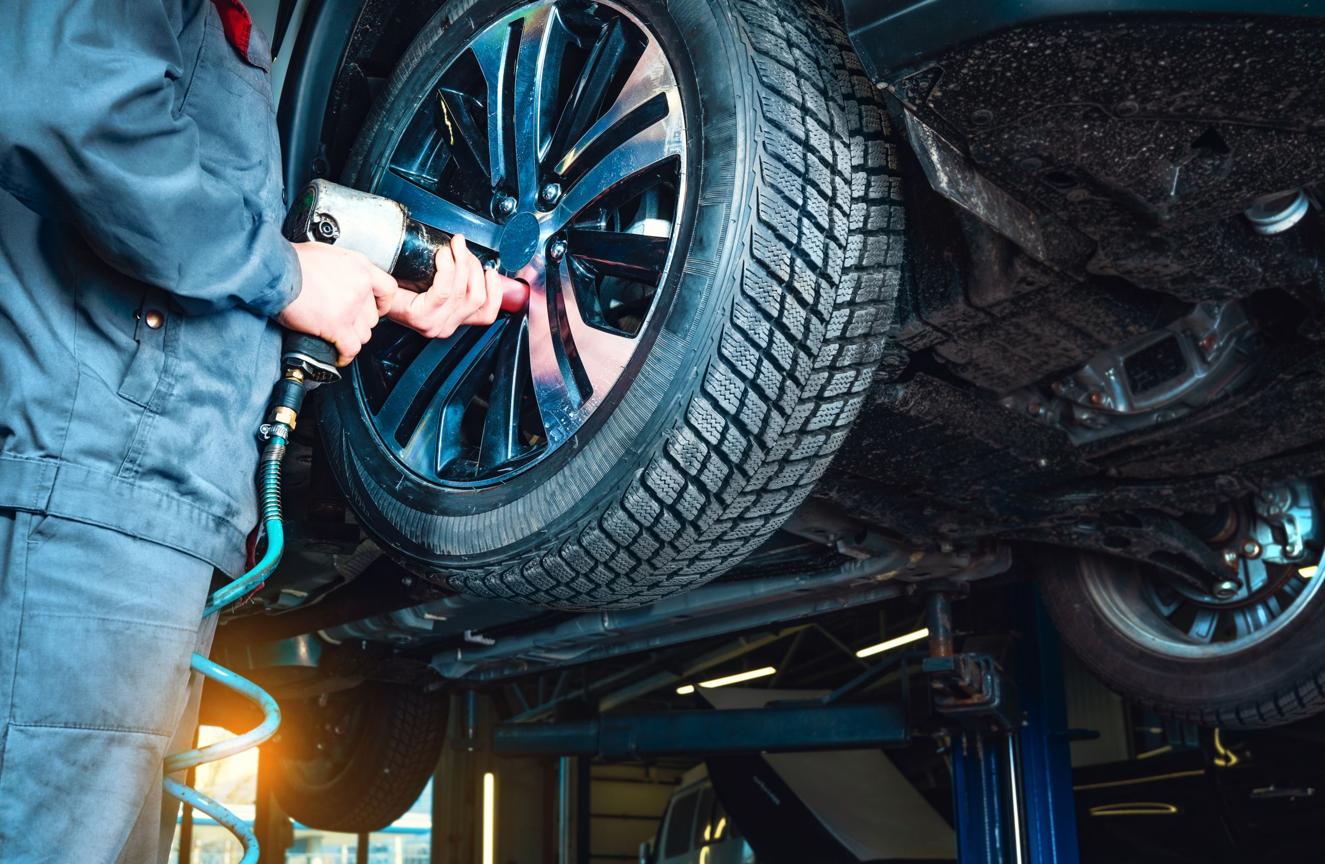 A mechanic removes the wheel using an electric drill symbolizing mobile tire repair services near me.