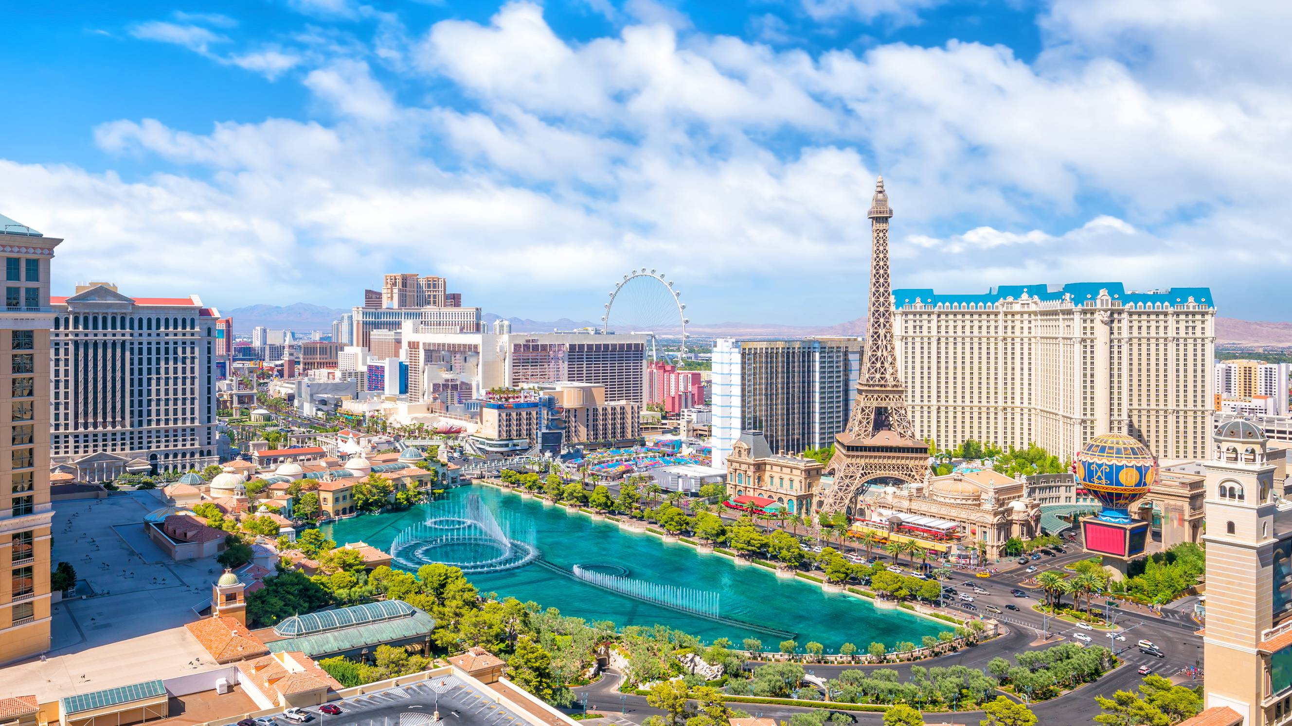 Aerial view of the Las Vegas Strip featuring the Bellagio fountains, the Eiffel Tower at Paris Las Vegas, and the High Roller observation wheel