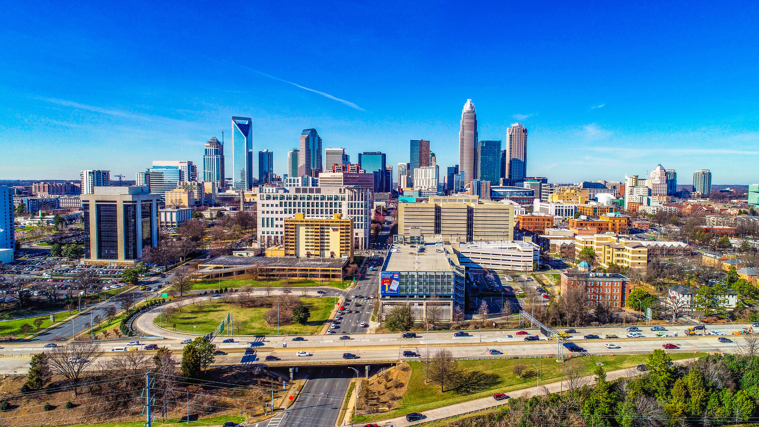 A wide panoramic aerial view of the sprawling Charlotte city skyline during the day.