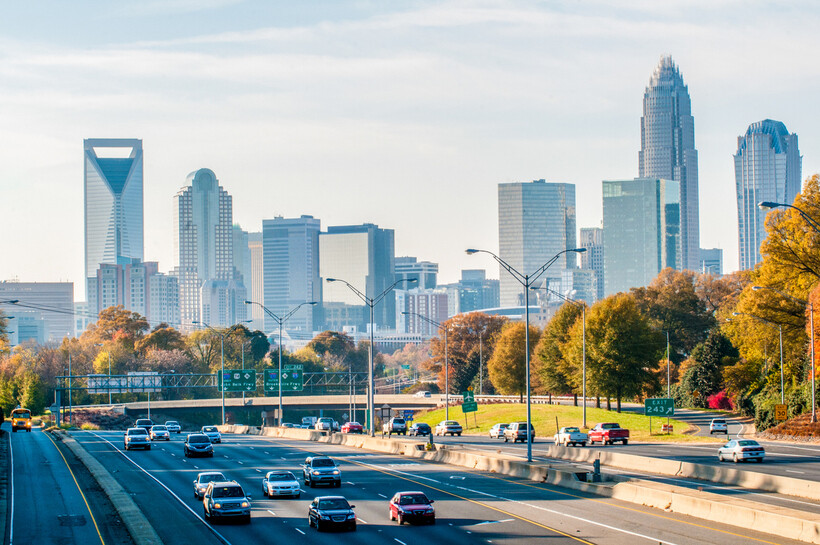 City buildings silhouetted against a colorful dusk sky during the fall season. - moving to Charlotte NC