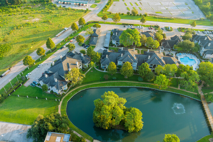 Bird’s-eye view of a typical Houston residential building with parking lots and landscaped grounds. - moving to Houston