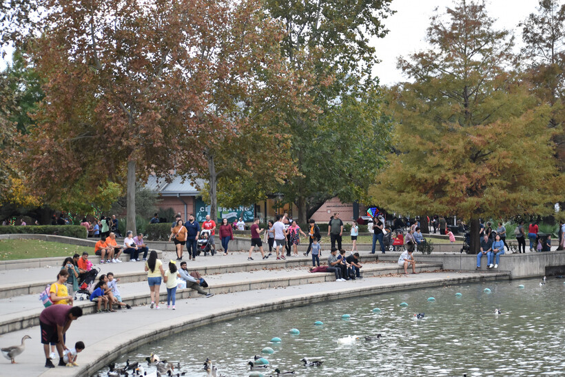 Families and visitors strolling along the lakeside path at Hermann Park in Houston. - moving to Houston
