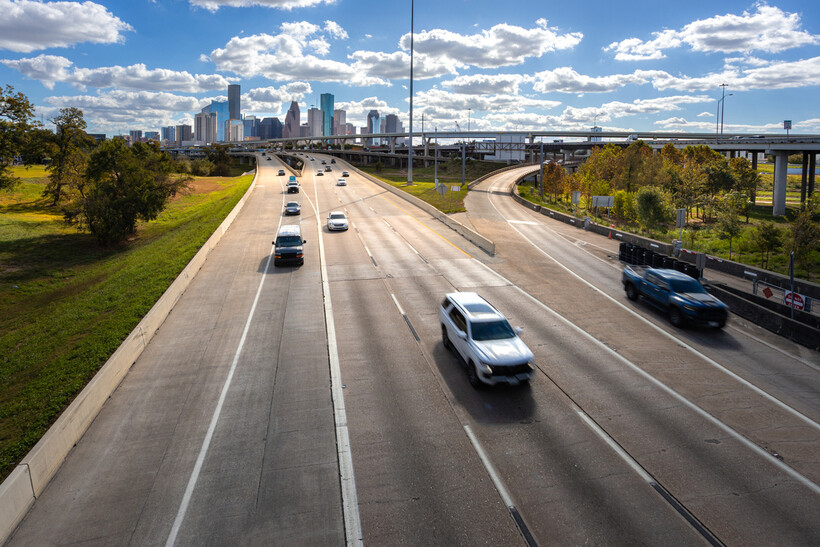 Multi-lane urban highway cutting through Houston with skyscrapers in the background. - moving to Houston