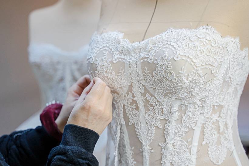 how much does tailoring cost - Close-up of couture wedding dress tailoring on a mannequin