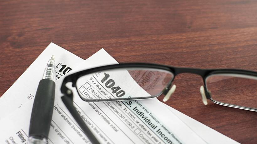 how much does a tax accountant cost - 1040 tax paperwork with black pen and eyeglasses