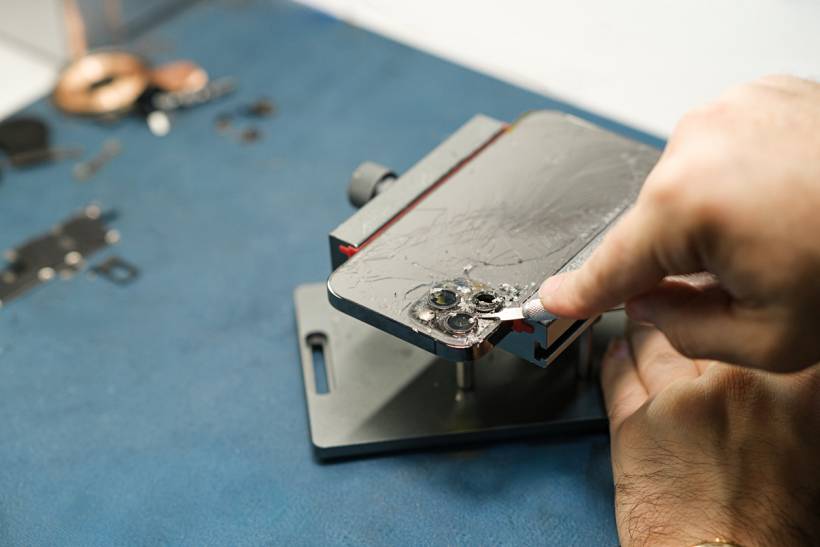 iPhone repair cost - Cracked iPhone back glass repair on workbench