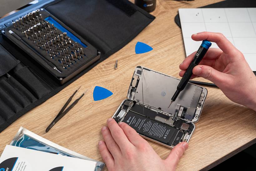 iPhone repair cost - Disassembled iPhone with repair tools on desk