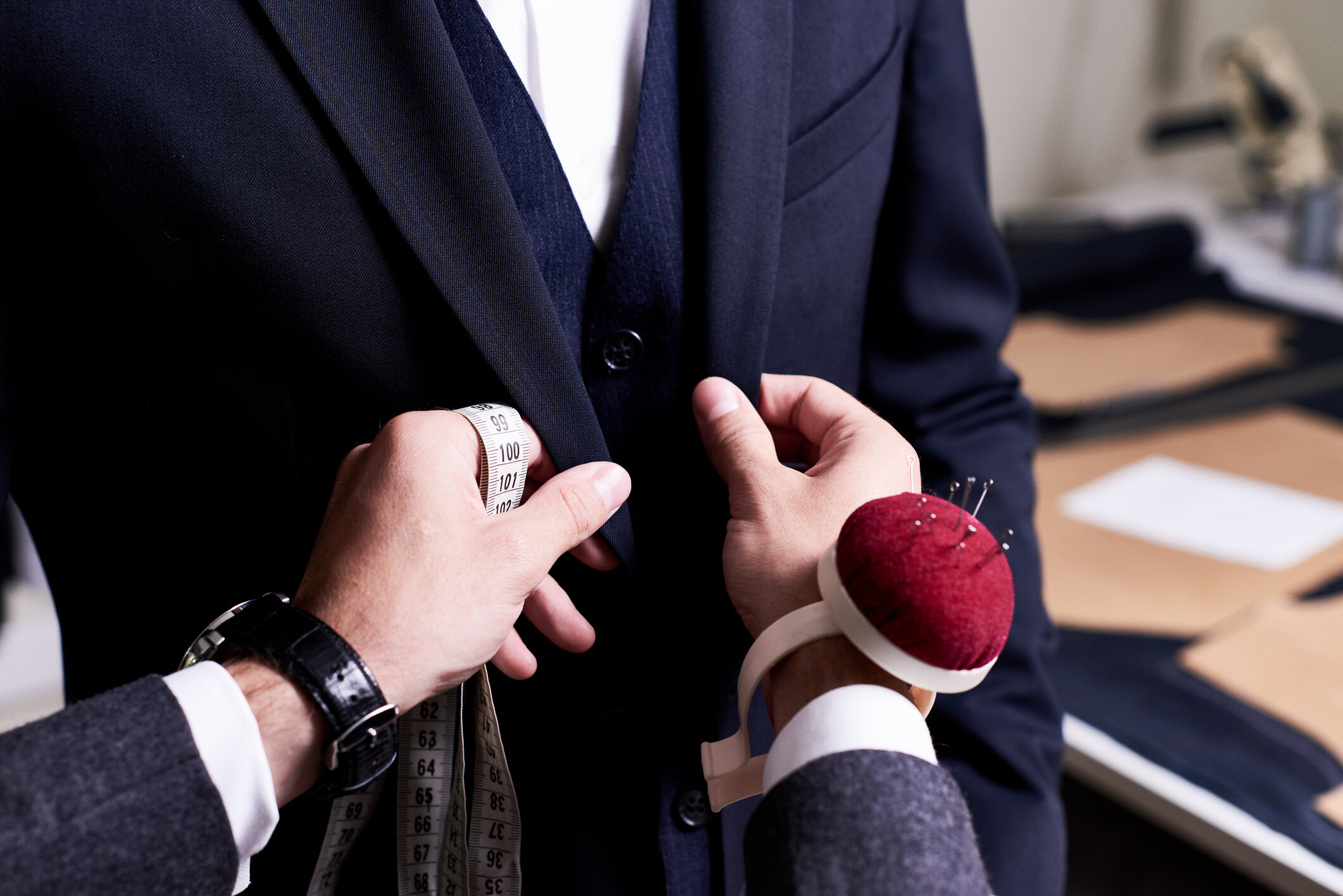 Close up of a tailor carefully pinning a suit jacket for adjustments. - suit alteration cost