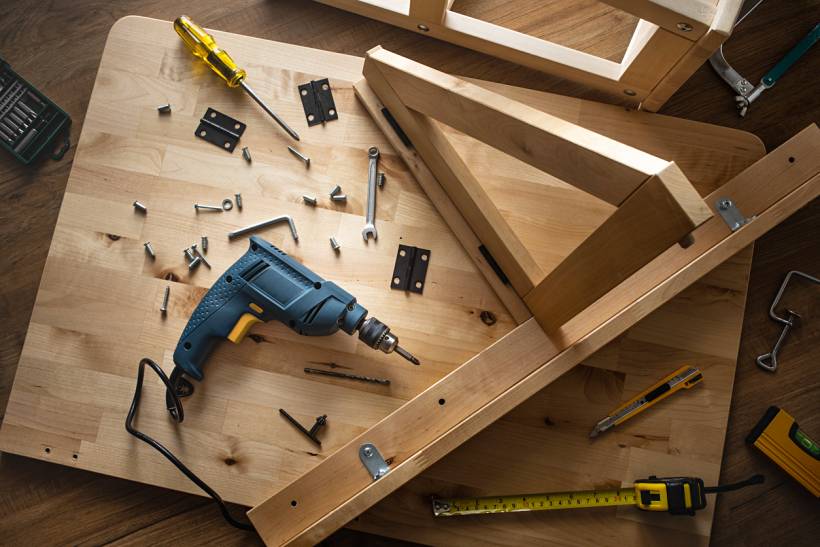 IKEA furniture assembly cost - Wooden furniture parts with drill, screws, and hand tools