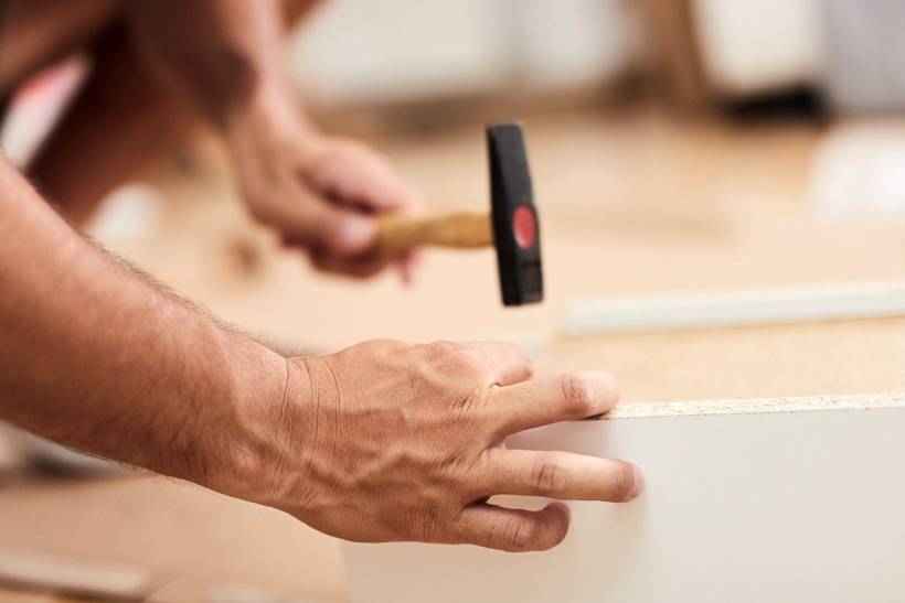 IKEA furniture assembly cost - Hands using a hammer during flat-pack furniture assembly