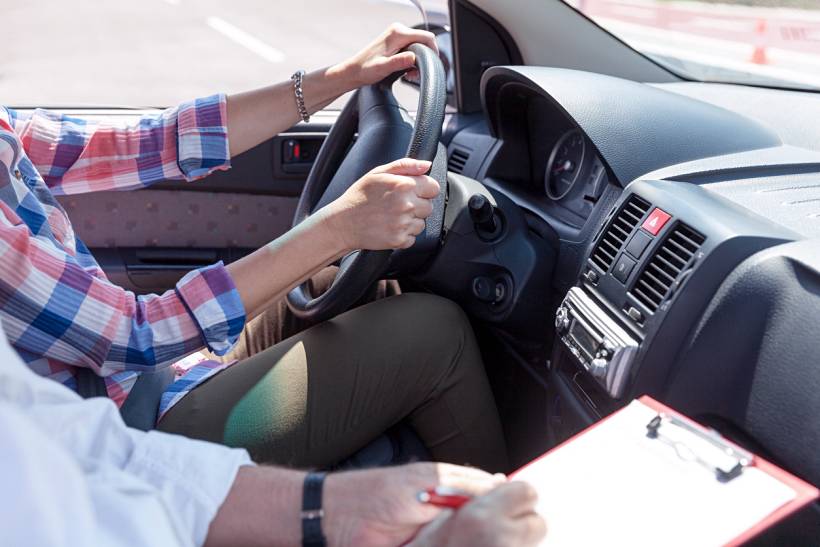 how much do driving lessons cost - Learner driver holding the steering wheel during an in-car driving lesson