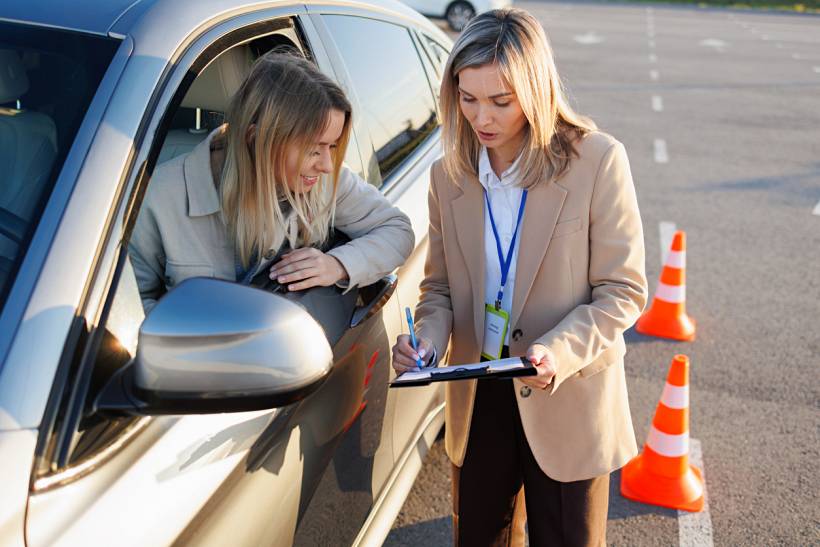 how much do driving lessons cost - Driving instructor completing paperwork beside a learner driver in a car