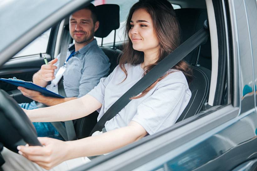 how much do driving lessons cost - Student driver behind the wheel with a driving instructor