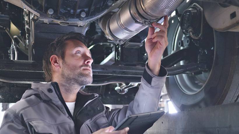 diesel particulate filter replacement cost - Mechanic inspecting vehicle exhaust system underneath a raised car