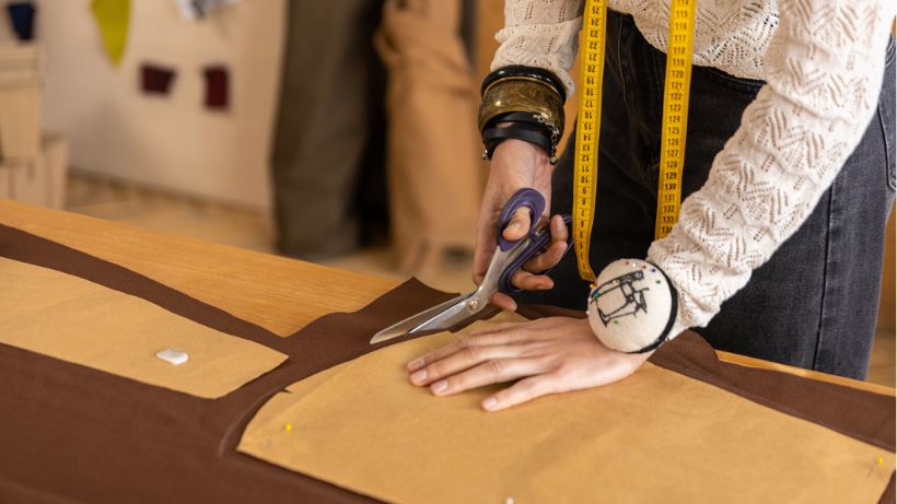 Seamstress cutting brown fabric using paper patterns