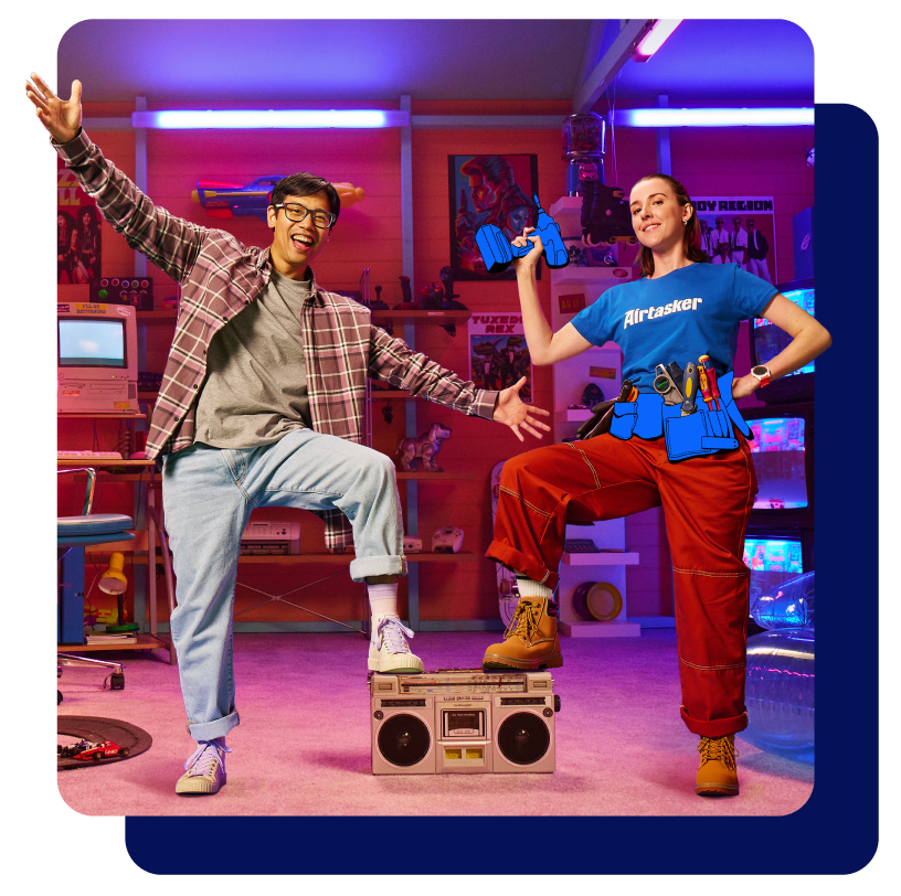 Two people standing in a 90s retro room. On the left, a man is smiling and throwing his hands up in the air in celebration. On the right, a woman holding a toolbox is smiling in satisfaction.